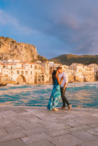 Cefalu Sicilya, Cefalu Sicilya sahilinde gün batımını izleyen çift, Sicilya 'da tatilde olan orta yaşlı erkek ve kadın. - Fotoğraf, Görsel