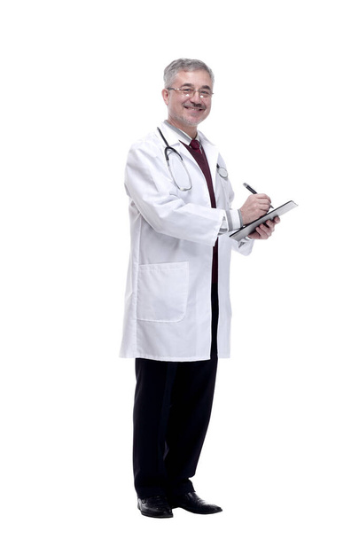 smiling doctor making notes in the clipboard. isolated on a white - Foto, afbeelding