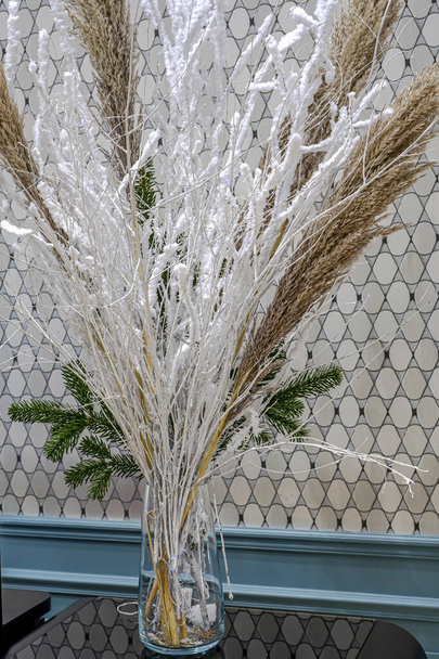 Bela composição de Natal de inverno com grama pampas e galhos secos decorados com neve artificial branca e pequena luz de brilho azul. Foto de alta qualidade - Foto, Imagem