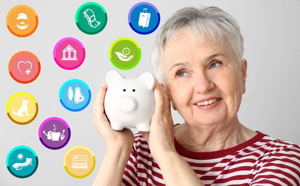 Oudere vrouw met spaarvarken bank schaven haar budget op grijze achtergrond - Foto, afbeelding