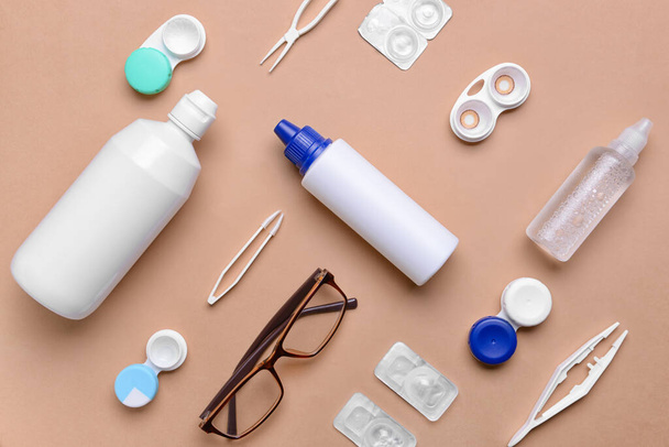 Containers with contact lenses, solutions, tweezers and eyeglasses on color background - Foto, afbeelding