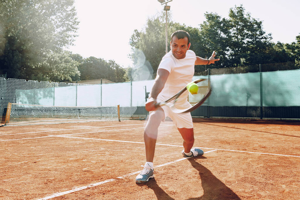 Fit man plays tennis on tennis field - Photo, image