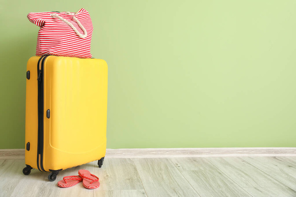 Packed suitcase with beach accessories near color wall - Foto, Imagen