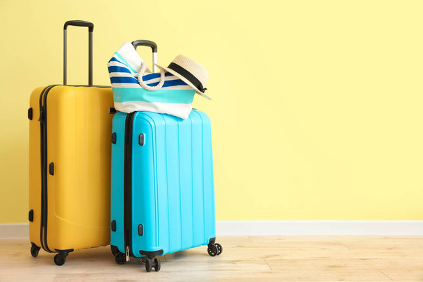 Plaj çantalı bavullar ve renkli duvarın yanında şapka. - Fotoğraf, Görsel