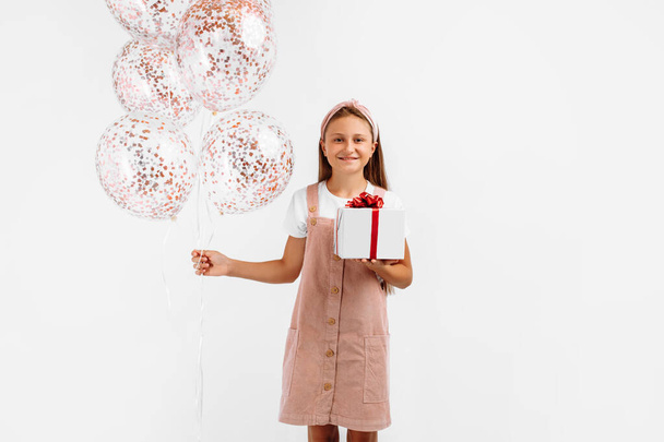 Beautiful happy little girl, child with balloons and gift box at holiday party, on isolated white background, Birthday celebration concept - Фото, изображение