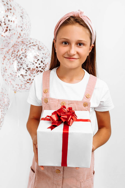 Beautiful happy little girl, child with balloons and gift box at holiday party, on isolated white background, Birthday celebration concept - 写真・画像