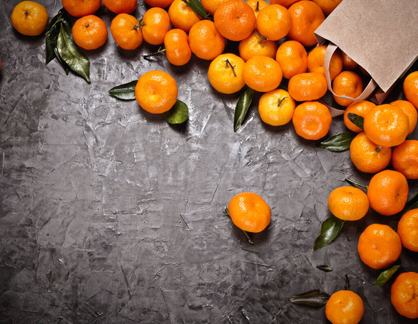 Colocação plana de saco de artesanato com tangerinas no fundo de concreto cinza, vinheta e espaço de cópia. Luz dura e sombras. - Foto, Imagem