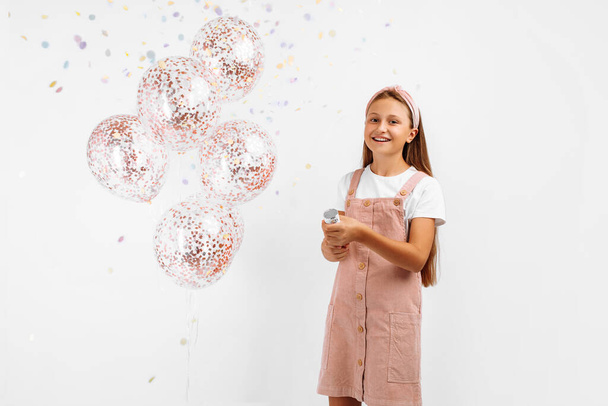 Happy excited little girl celebrating and exploding up colorful confetti, over isolated white background - Foto, Imagem
