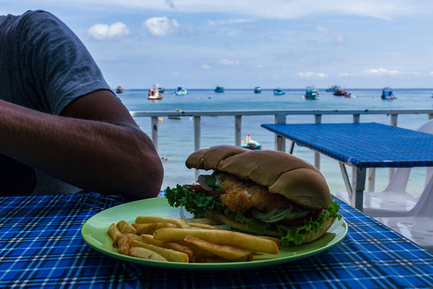 タイ島の海のレストラン、グリーンプレート上で無料でファーストフードチキンバーガー。青いテーブルの屋外家具 - 写真・画像