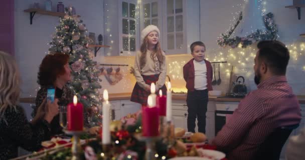 Adorables niños cantando poemas en la cena de Navidad con la familia - Imágenes, Vídeo