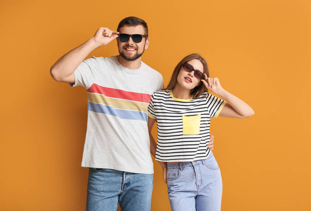 Junges Paar mit stylischer Sonnenbrille auf farbigem Hintergrund - Foto, Bild