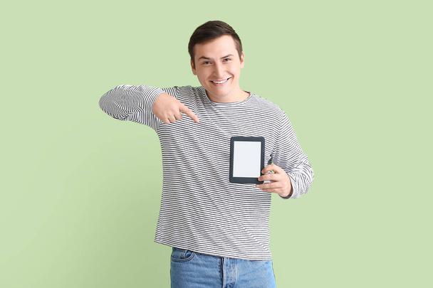 Νεαρός άνδρας με e-reader στο φόντο χρώμα - Φωτογραφία, εικόνα