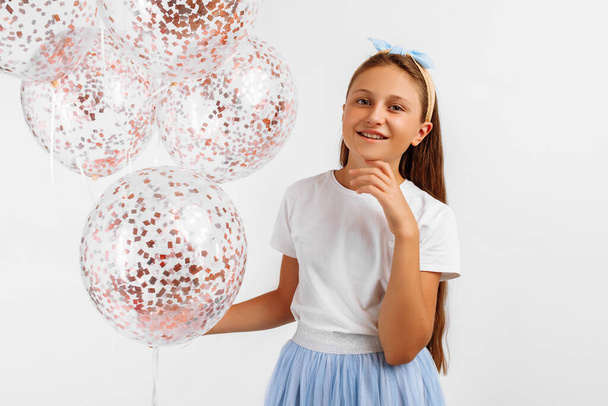 Happy young girl celebrating and holding colorful balloons isolated on white background. Birthday party - Zdjęcie, obraz