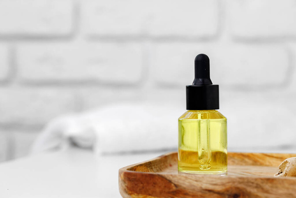 Botella de aceite cosmético amarillo en bandeja de madera de cerca - Foto, imagen