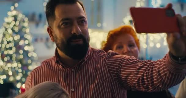 Mies keräämässä perhettä selfielle jouluna - Materiaali, video