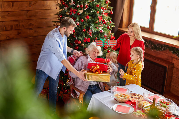 boldog idős nő kap karácsonyi ajándékokat gyermekei és unokái - Fotó, kép