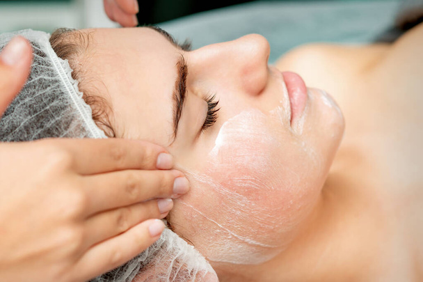 Giovane donna ottenere massaggio facciale con gli occhi chiusi da estetista nel salone di bellezza - Foto, immagini