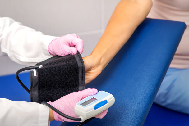 Sairaanhoitaja tai naislääkäri laittaa tonometrin käsivarteen nuoren naisen sairaalassa - Valokuva, kuva