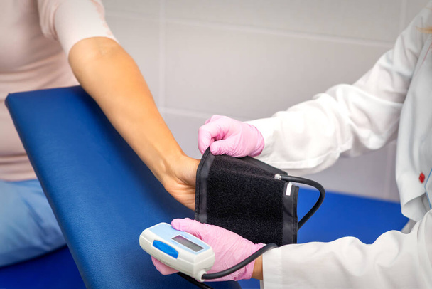 Infirmière ou femme médecin met tonomètre sur le bras de la jeune femme à l'hôpital. Concentration sélective - Photo, image