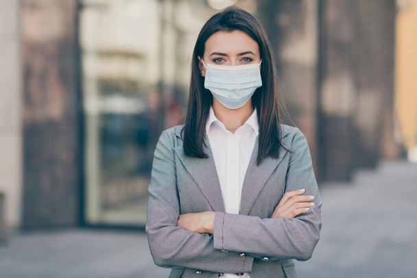 Photo of serious beautiful business lady crossed hands wear respiratory mask epidemic look job outside in city outdoors - Fotografie, Obrázek