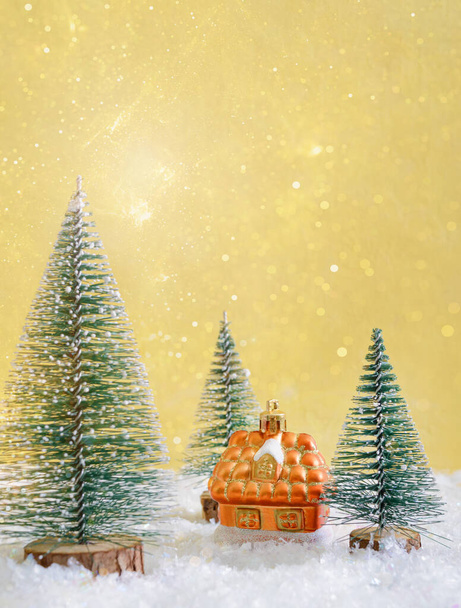 Барвистий різдвяний іграшковий будинок на снігу серед ялинки. Фон зі святковими вогнями. Затишний будинок купує концепцію. Прекрасна різдвяна листівка, місце для копіювання
. - Фото, зображення