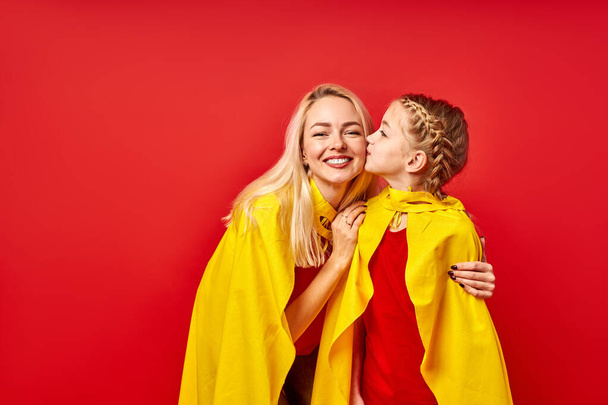 pretty woman and child girl in superhero costumes posing - Foto, afbeelding