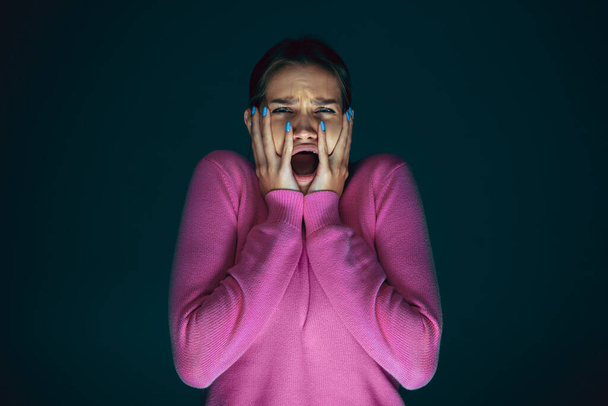 Close up portrait of young crazy scared and shocked woman isolated on dark background - Foto, Bild