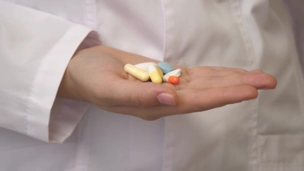 Pain reliever pills in the female hand of a medical professional in a white coat. Capsules with medicines, taking medication, healthcare, pharmacy and treatment concept, close up view - Footage, Video
