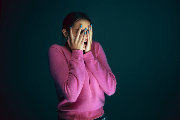 Close up portrait of young crazy scared and shocked woman isolated on dark background - Φωτογραφία, εικόνα