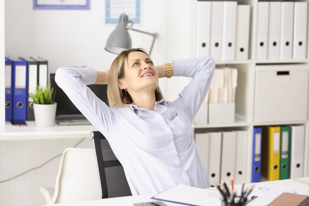 Happy businesswoman sits at her work table and looks up - Φωτογραφία, εικόνα
