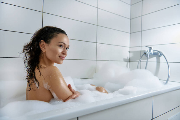 The beautiful woman takes a bath while sitting in foam - Fotó, kép