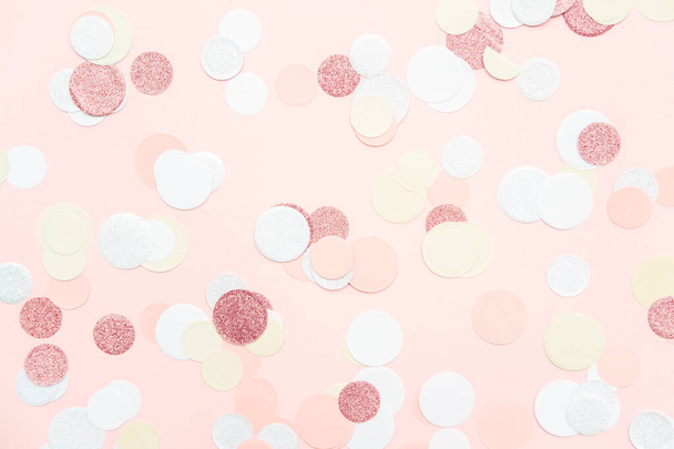 Multicolor roze, goud en wit confetti op de lichte perzik roze achtergrond, vakantie viering achtergrond - Foto, afbeelding