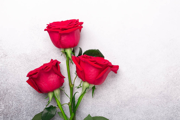 Three red roses on stone background. Top view. Copy space - Image - Foto, Imagem