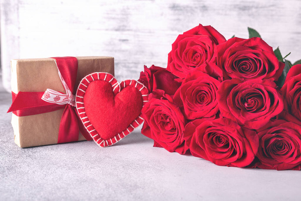 Valentines day greeting card. Red roses, gift box and decorative textile heart on stone background. Top view. Copy space - Image - Fotoğraf, Görsel