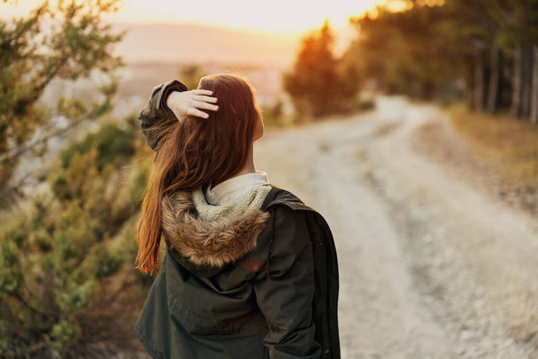 Женщина в теплой куртке на природе прогулка по дорожному пейзажу свежий воздух - Фото, изображение