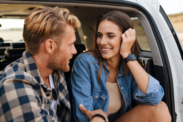 Smiling young couple sitting in back of car - Photo, image