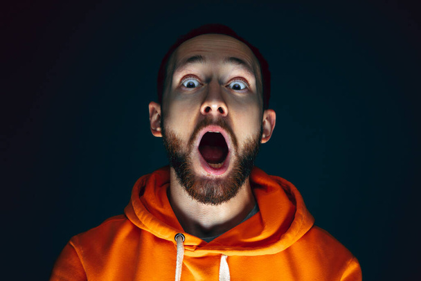 Close up portrait of crazy scared and shocked man isolated on dark background - Photo, Image