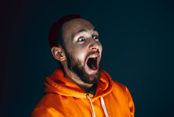 Close up portrait of crazy scared and shocked man isolated on dark background - Fotografie, Obrázek