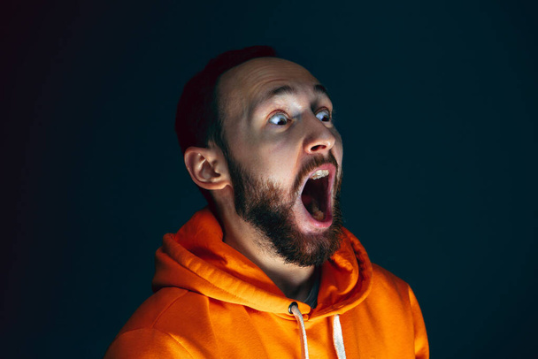 Close up portrait of crazy scared and shocked man isolated on dark background - Photo, image