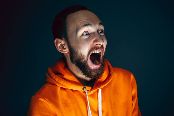 Close up portrait of crazy scared and shocked man isolated on dark background - Фото, изображение