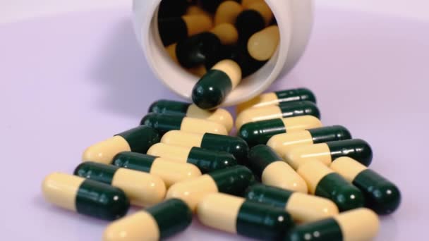 Viele medizinische Tabletten zur Behandlung in gelben grünen Kapseln auf einem Drehtisch. Nahaufnahme von Medikamenten, Vitaminen, Medikamenten. - Filmmaterial, Video