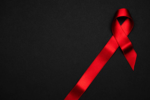 HIV desteği. HIV dünyasında siyah zemin üzerinde kırmızı kurdele sembolü. Farkındalık yardımcıları ve kanser. Yaşlanma Sağlık Ay konsepti - Fotoğraf, Görsel
