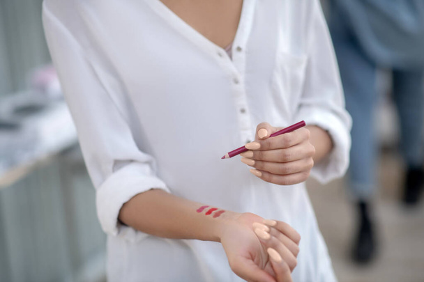 Female hands trying red lip liner on wrist - Foto, Imagem