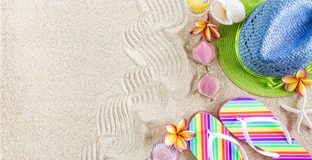 Blauer und grüner Strohhut und bunte Flip Flops im Sand mit Muscheln und Frangipani-Blumen. Sommerzeit am Strand Konzept, Kopierraum  - Foto, Bild