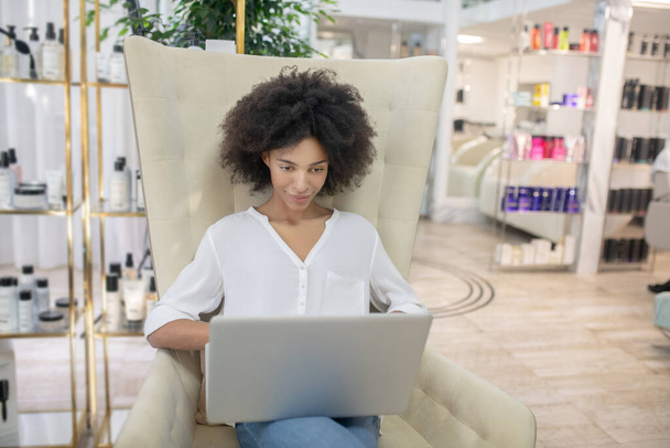 Attentive woman looking at laptop sitting in armchair - Foto, Imagen