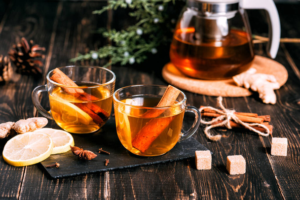 Glass cup of hot ginger tea with lemon on dark wooden table. - Valokuva, kuva