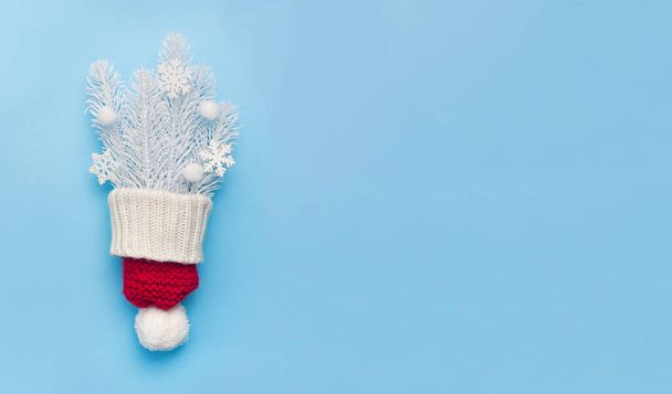 Vánoční přání s červeným kloboukem a bílými jedlovými větvemi a sněhovými vločkami na modrém podkladu. Vánoční pohlednice s místem pro váš text. Šťastný nový rok - Fotografie, Obrázek