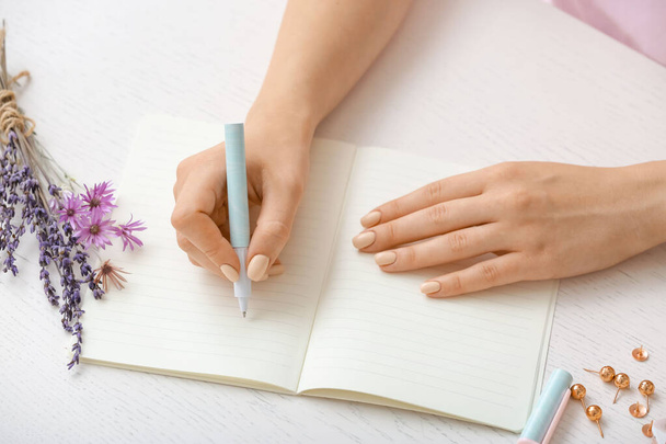 Schrijvende vrouw in notitieboekje met pen - Foto, afbeelding