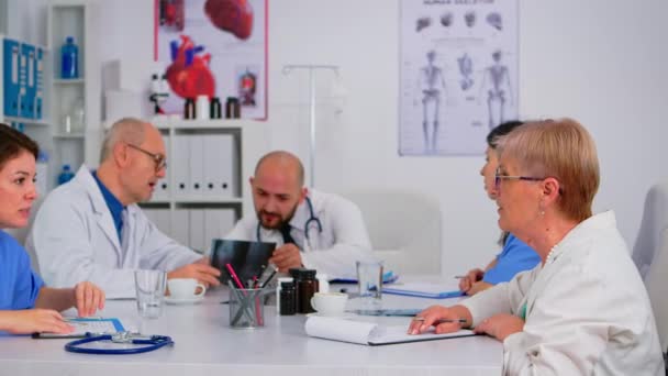 Médicos en reunión de personal sentados uno frente al otro hablando - Metraje, vídeo