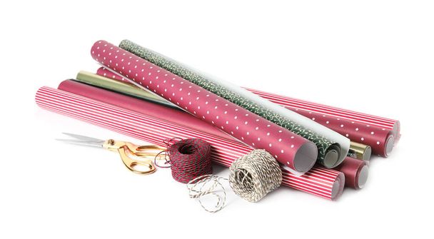 Different colorful wrapping paper rolls, scissors and ropes on white background - Foto, Bild